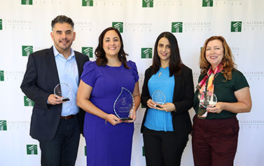 The four 2024 Capstone Award stand together in a row while holding their awards in front of a step-and-repeat banner with the California JPIA's logo.